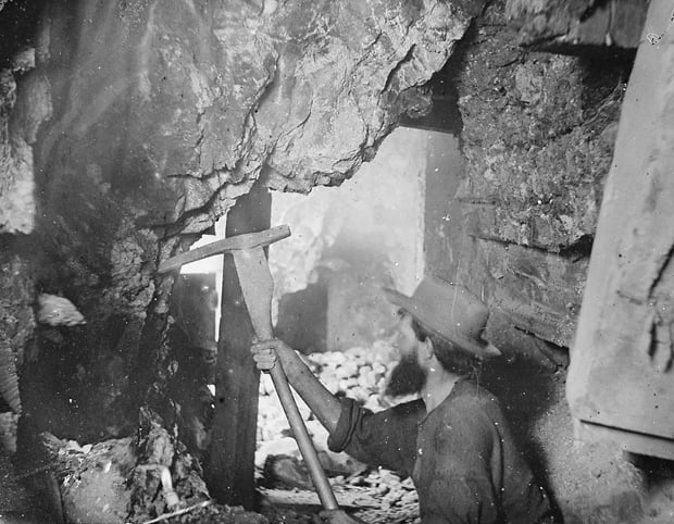 Miner working nine hundred feet underground at the Savage and the Gould and Curry mines on the Comstock Lode in Virginia City, Nevada. Taken in 1867.