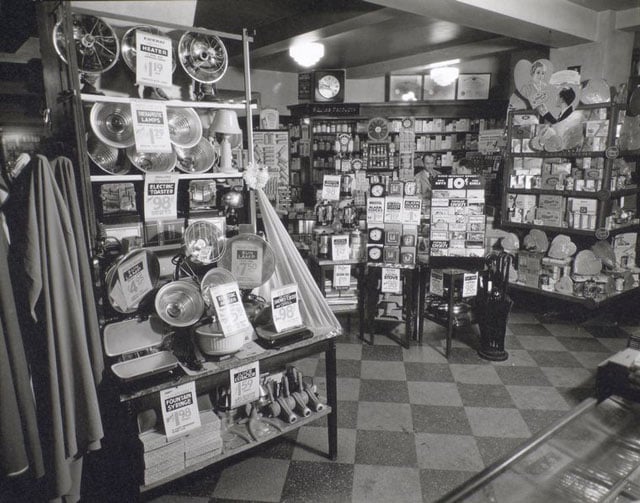 Whelan's Drug Store, 44th Street and Eighth Avenue, Manhattan. Man waits on customer in background, displays of electrical appliances, clocks, and a Valentine's Day display of candy.