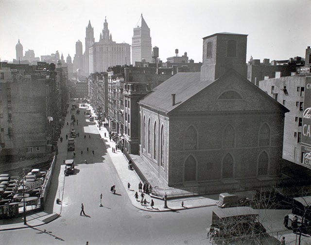 General view, looking southwest to Manhattan from Manhattan Bridge, Manhattan. Looking down Monroe Street toward Municipal building and financial district; children play on corner near church, parking lot, left.