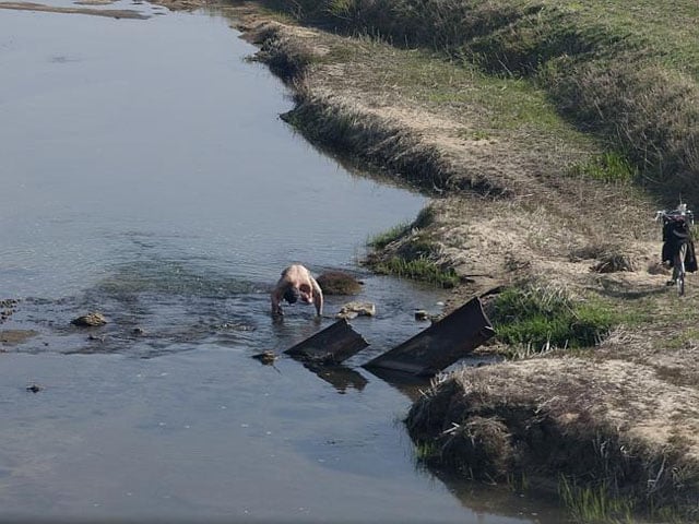 A man in a shallow river.