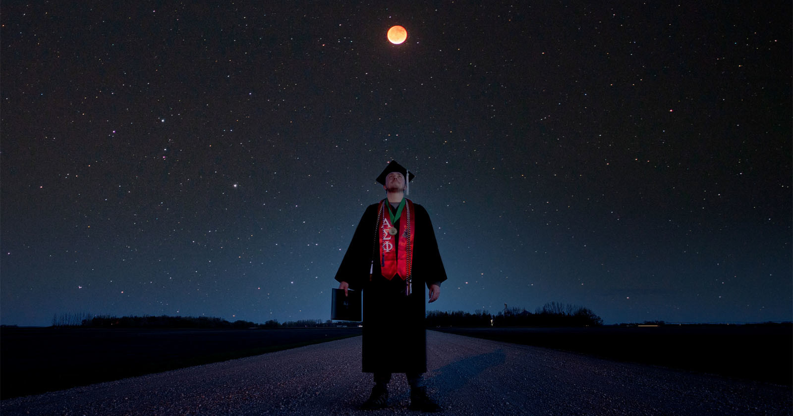 Astrophysics Student Takes Graduation Photo Under a Total Lunar Eclipse