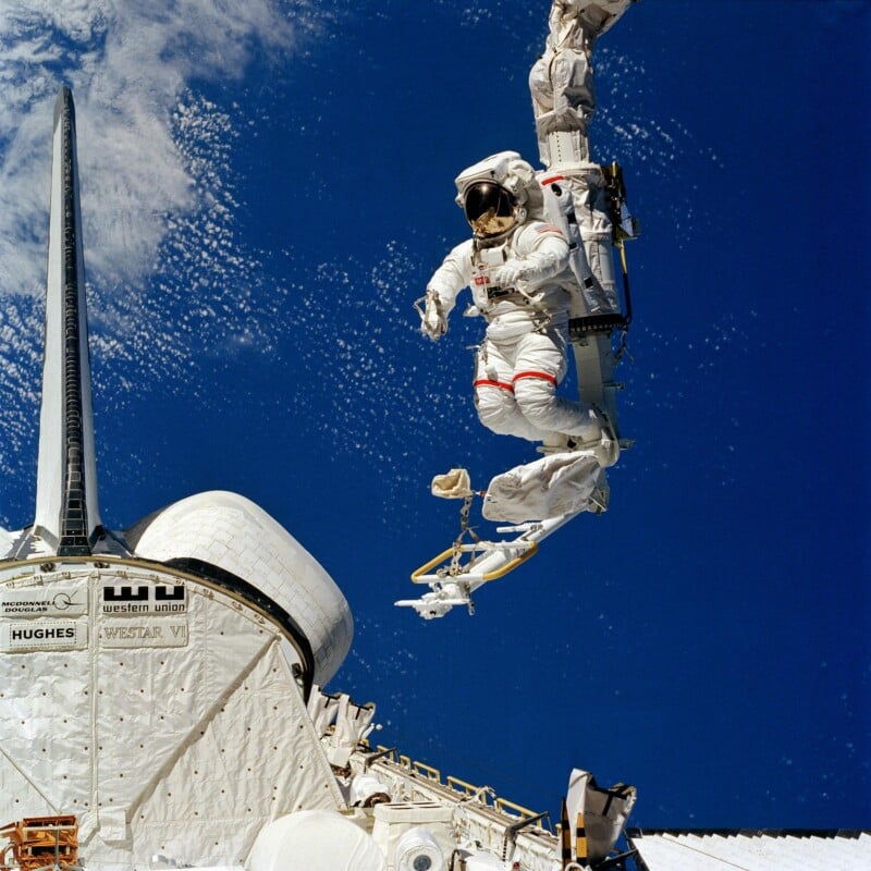 The feet of Bruce McCandless II are anchored in the Mobile Foot Restraint (MFR) and moved around by the Remote Manipulator System (RMS).