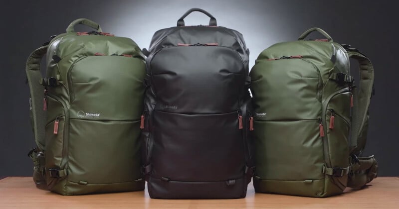 Two green Shimoda backpacks sit next to a black version on a table in front of a black gradient background.