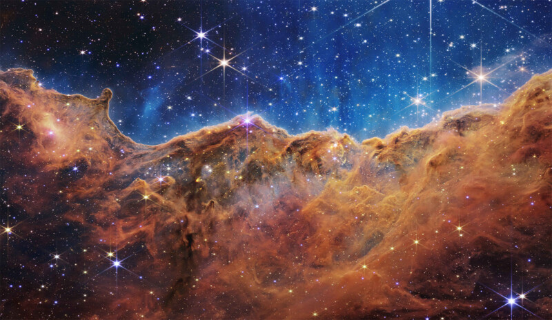A vibrant image of a cosmic region with glowing stars and intricate clouds of gas and dust in brilliant shades of orange and gold, evoking a sense of depth and vastness in the universe.