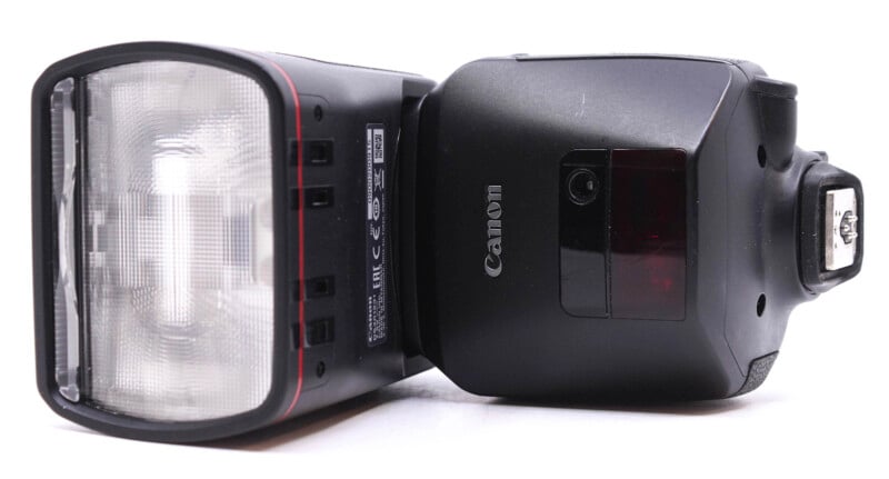 Side view of a Canon camera flash unit, showing the transparent flash head and the canon logo, against a white background.