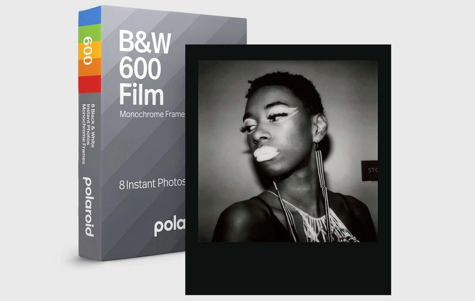 A black and white polaroid photo depicting a woman with striking makeup and earrings, next to a box of b&w 600 film by Polaroid. the image emphasis is on artistic expression through monochrome filters.