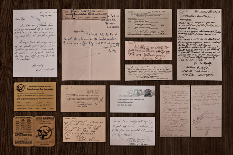 A collection of vintage handwritten letters, postcards, and documents arranged neatly on a wooden surface, showing various handwriting styles and paper types in shades of brown and beige.