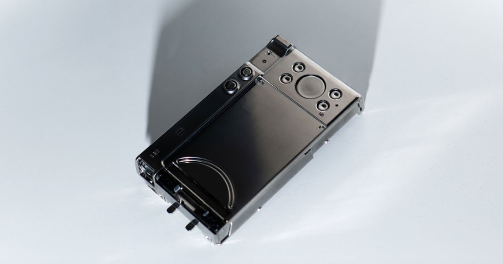 A retro-style portable music player with a metallic finish, visible buttons, dials, and a circular touchpad, placed on a plain light surface.