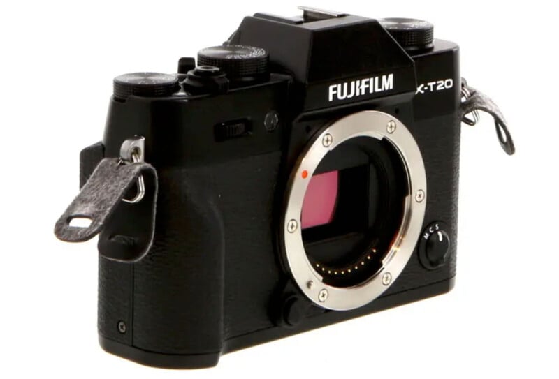 A black Fujifilm X-T20 mirrorless digital camera body with no lens attached, showing the sensor inside the lens mount. The camera has dials and straps on both sides.