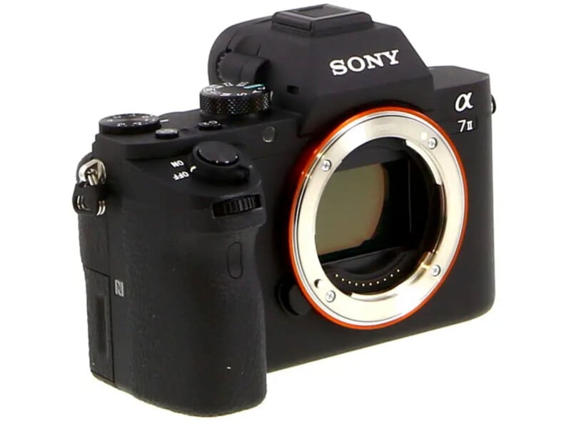 A black Sony Alpha a7 II mirrorless digital camera body is shown without a lens, revealing the sensor and lens mount. The camera features various dials and buttons, with the Sony logo visible on top.