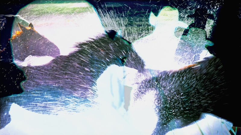 Abstract image with overlapping silhouettes of horses and figures in cowboy hats, with dynamic streaks and splashes of light and color, creating a sense of motion and energy.