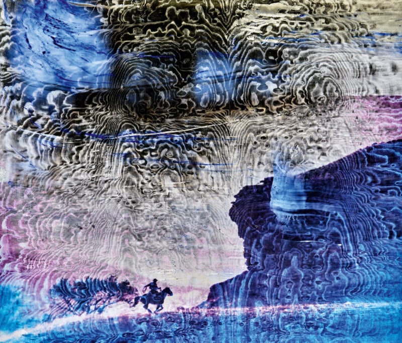 A lone cowboy on horseback rides across a vibrant, surreal landscape with swirling, textured blue, white, and purple patterns dominating the sky and terrain.
