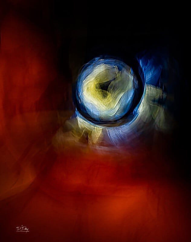 Abstract image featuring a swirling, circular pattern of blue, yellow, and white light at the center, surrounded by a dark background with deep red and orange hues blending into each other.