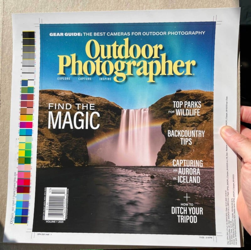 A person holds a magazine titled "Outdoor Photographer" featuring a scenic waterfall, rainbow, and rocky landscape on the cover with article headlines about wildlife, backcountry tips, and aurora photography in Iceland.