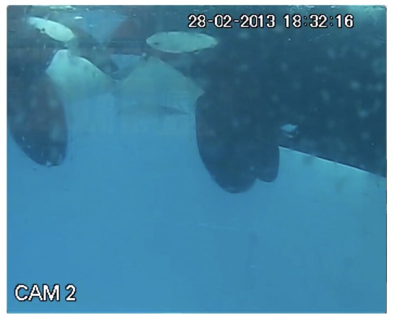 Underwater camera view showing the propellers of a vessel. The date and time "28-02-2013 18:32:16" and "CAM 2" are displayed on the image. The water is blue and somewhat murky.