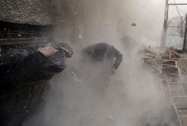 Free Syrian Army fighters run for cover as a tank shell explodes on a wall during heavy fighting in the Ain Tarma neighbourhood of Damascus