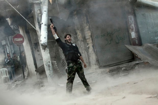 Rebel fighter gestures for victory after firing a missile toward a building where Syrian troops were hiding. (c) Narciso Contreras, AP