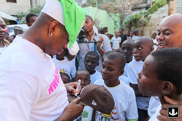 NE-YO signing his hat before exchanging hats with a child at an orphanage in Haiti
