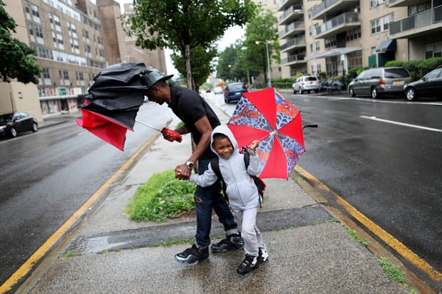 Kwazi Peters and his son, Elijah, 5, both of Yonkers, walk along Riverdale Avenue while on their way to a deli before heading home on a rainy day in Yonkers. (June 10, 2013) 