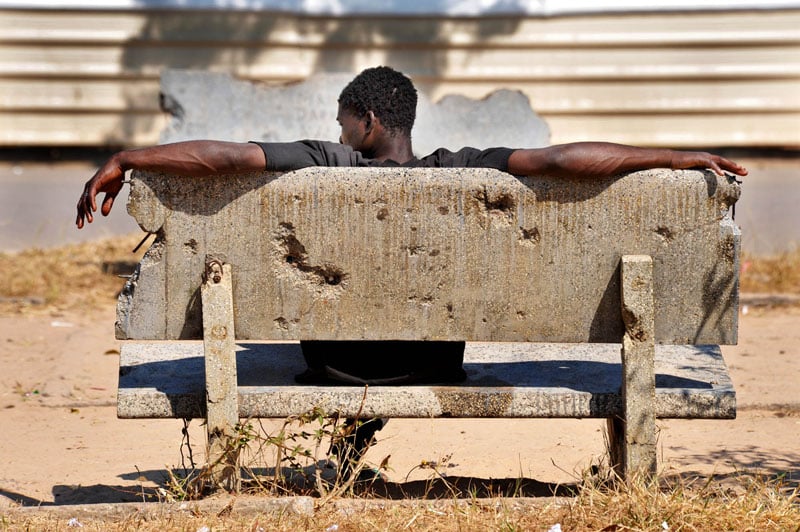 A man sits on a bullet-riddled bench following a decade of civil war which has left Angola scared.