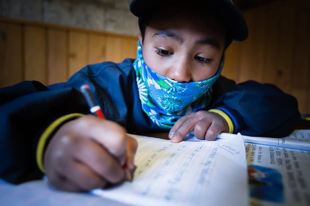 A young Sherpa boy doing his English homework.