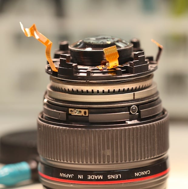 Canon 35mm f/1.4 L with rear barrel removed, showing 4 plastic posts that the lens mount attaches to.