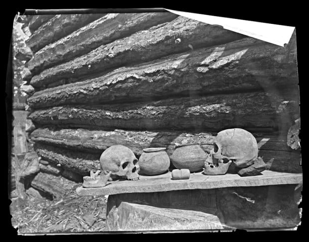 Skulls, ceramic pots, and stone object, outside log cabin, Mexico