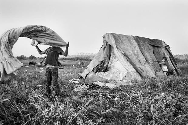 After a twin family shack got demolished due to a quarrel, the kids are dusting the sheets from their provisional tent. May 2013.