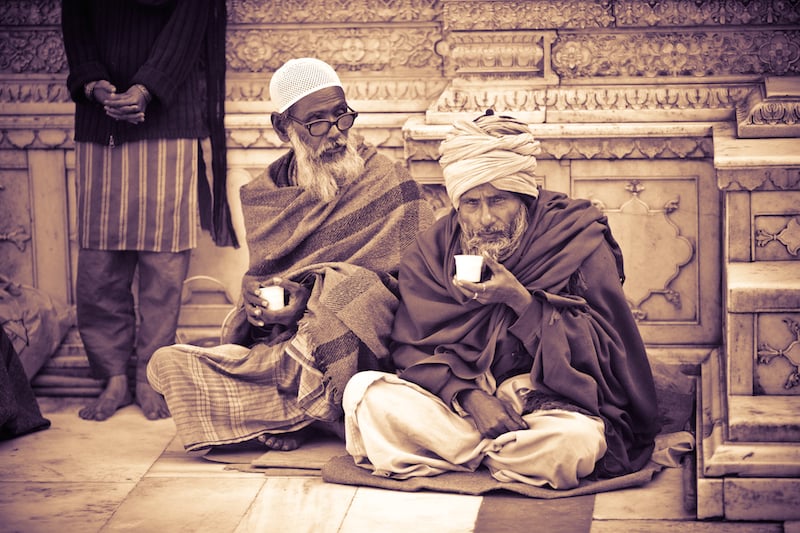 Delhi. Two older men drink chai at Nizzamudin Shrine.