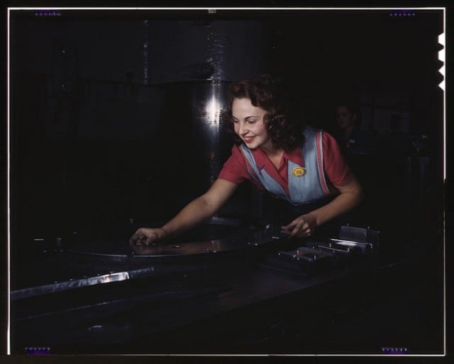 A woman preparing metal parts to go through a multi-ton hydropess. North American Aviation, Inc. 1942.