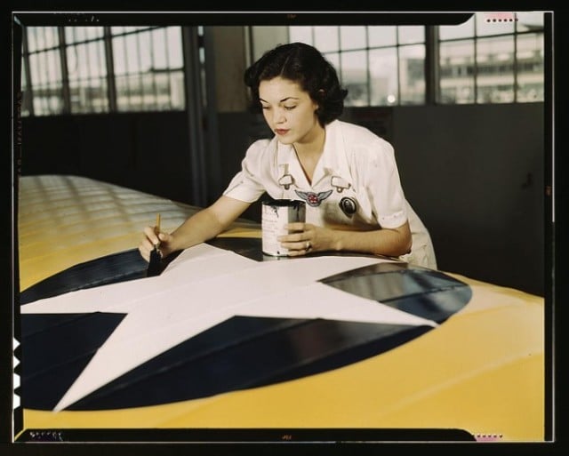 Mrs. Irma Lee McElroy painting the American insignia on airplane wings. Naval Air Base in Corpus Christi, Texas in August, 1942