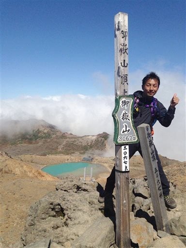 Hideomi Takahashi stands at the summit of the volcano.