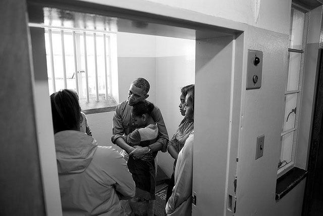 President Barack Obama and First Lady Michelle Obama, along with daughters Sasha and Malia, stand in former South African President Nelson Mandela's cell as they listen to former prisoner Ahmed Kathrada during their tour of Robben Island Prison on Robben Island in Cape Town, South Africa, June 30, 2013.