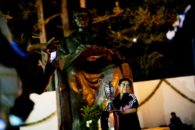 A player from Guelatao poses for a photograph in front of the town's statue of Benito Juárez.