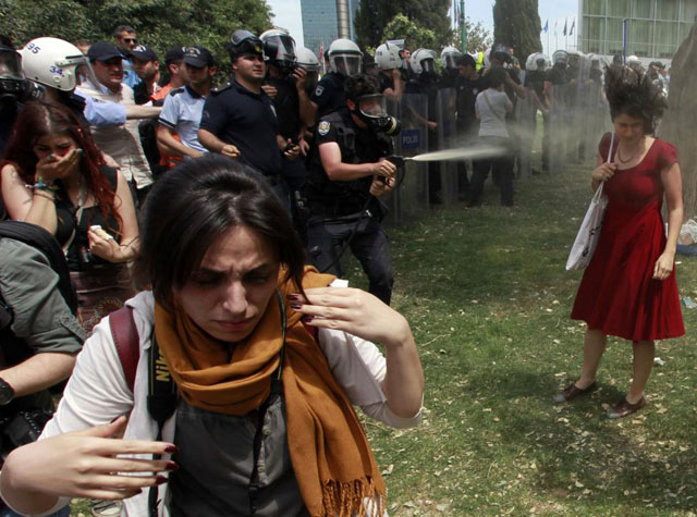 A Turkish riot policeman uses tear gas as people protest against the destruction of trees in a park brought about by a pedestrian project, in Taksim Square in central Istanbul, May 28, 2013. Osman Orsal.