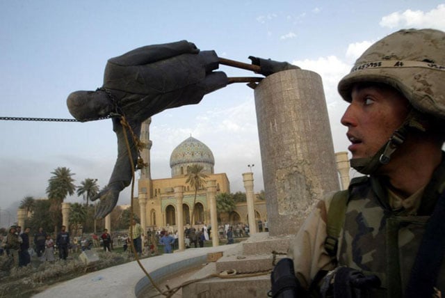 U.S. Marine Corp Assaultman Kirk Dalrymple watches as a statue of Iraq's President Saddam Hussein falls in central Baghdad. April 9, 2003. Goran Tomasevic.
