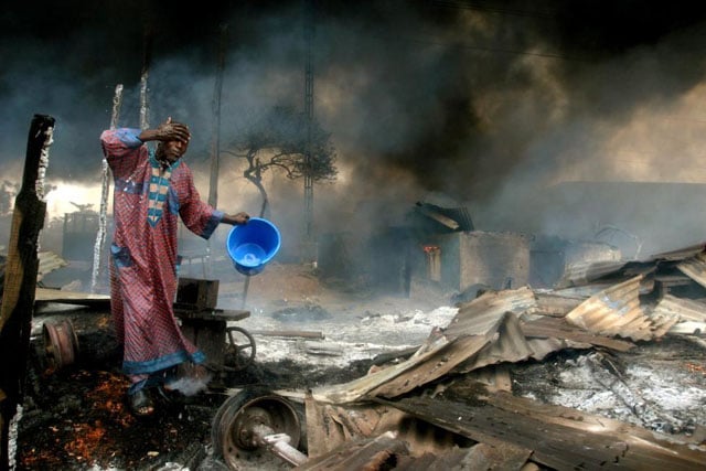 A man rinses soot from his face at the scene of a gas pipeline explosion near Nigeria's commercial capital Lagos, Nigeria, December 26, 2006. Akintunde Akinleye.