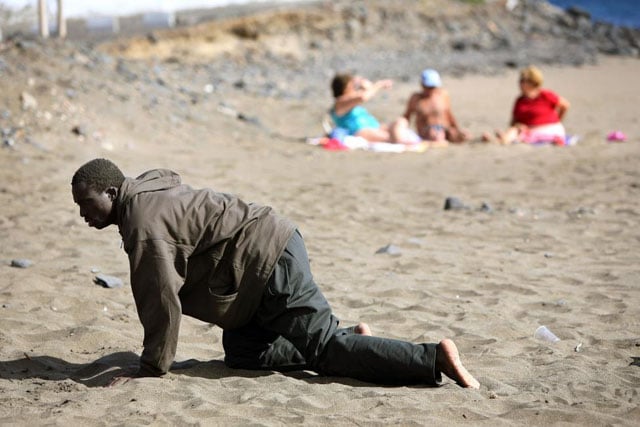 A would-be immigrant crawls on the beach after his arrival on a makeshift boat on the Gran Tarajal beach in Spain's Canary Island of Fuerteventura, May 5, 2006. Juan Medina.