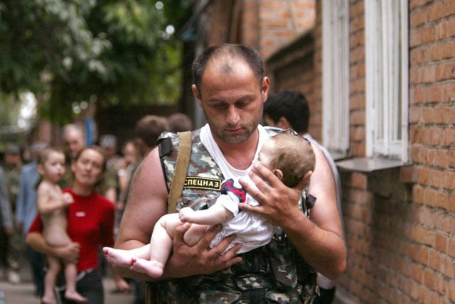 A Russian police officer carries a released baby from a school seized by heavily armed masked men and women in the town of Beslan in the province of North Ossetia near Chechnya, September 2, 2004. Viktor Korotayev.