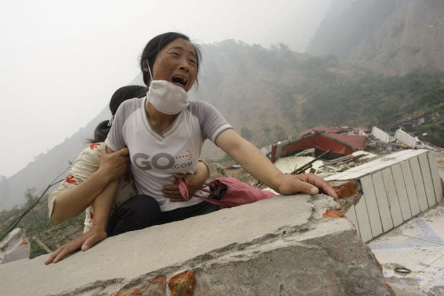 A woman cries as she cannot find her 4-year-old daughter and husband on the top of the ruins of a destroyed school in earthquake-hit Beichuan county, Sichuan province, May 17, 2008. Jason Lee.