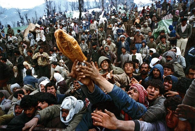 Frantic Kurdish refugees struggle for a loaf of bread during a humanitarian aid distribution at the Iraqi-Turkish border, April 5, 1992. Yannis Behrakis.