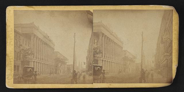 Photograph shows activity on Meeting Street in Charleston, with the Classic Revival style Charleston Hotel on the left.