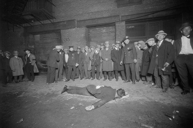A crowd gathering around the body of a shooting victim.