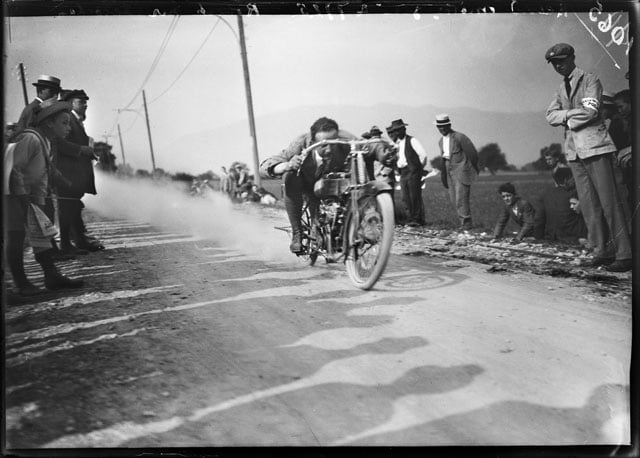 Motorcyclist Robert dashes past a kilometer post with his 500ccm machine by the Swiss producer Motosacoche SA Dufaux & Cie at a motorcycle race in Geneva, Switzerland, 1915. (KEYSTONE/ Photopress-Archive/ Jules Decrauzat) Glasplate