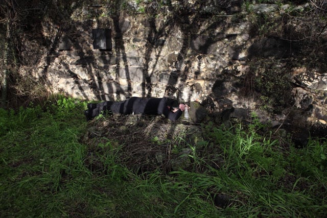 An Orthodox Hassidic Jew lying on a grave.