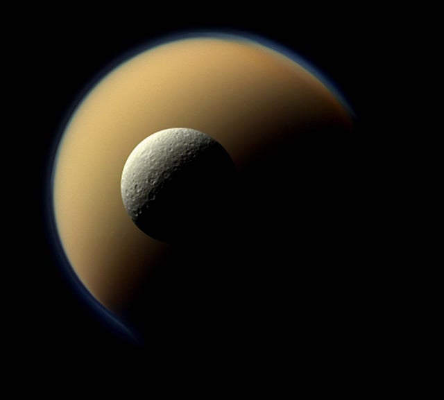 Saturn's moon Rhea hovering in front of Saturn's largest moon, Titan.