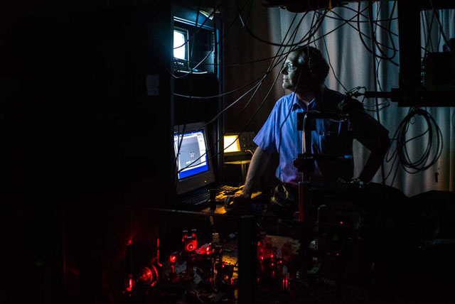 After pumping single molecules with a red laser beam, W.E. Moerner examines them on a computer screen at one of the super-resolution imaging setups in his laboratory.