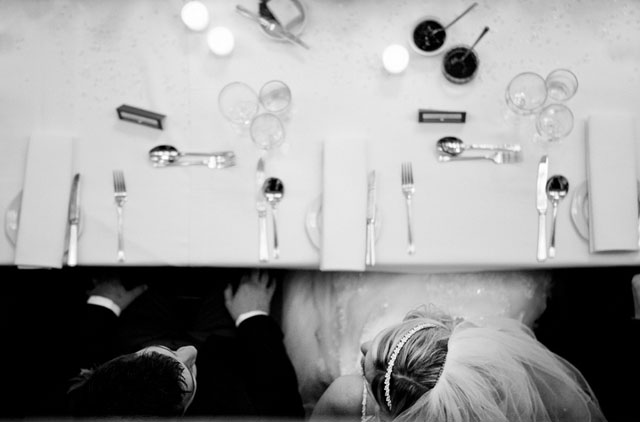 A bride and groom await their wedding breakfast. Captured from a balcony above them.