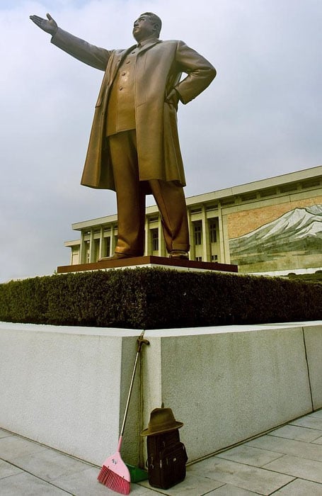 An offensive photo of a broom leaning against the statue of Kim Il Sung in Pyongyang.