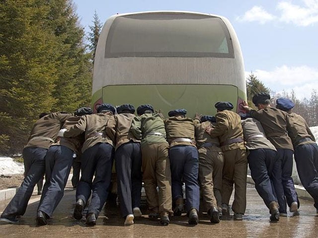 People pushing a broken down bus -- not a nice photo for a government intend on preserving a pristine image.